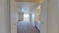 This well-proportioned single-story residence offers four bedrooms, two bathrooms, and a thoughtfully arranged layout across a generously sized floor plan. The living room serves as the centerpiece of the home, featuring a classic fireplace flanked by built-in shelving and cabinetry, and expansive floor-to-ceiling sliding glass doors that open onto a balcony with open exterior views. Plush carpeting runs throughout the living areas and bedrooms, contributing to a warm, comfortable ambiance.

The kitchen is well-equipped with abundant white cabinetry, tile flooring, a double wall oven, gas cooktop, refrigerator, and a built-in desk area. An adjacent dining room provides additional cabinetry and a dedicated workspace nook with subway tile detailing. The four bedrooms are carpeted and neutrally finished; the spacious primary bedroom includes sliding glass door access to the balcony. Secondary bedrooms are comfortably sized with ample wall space. The bathrooms feature tile flooring, tub-shower combinations, and vanity storage. Multiple hallways connect the rooms, creating a functional and organized flow throughout the residence.