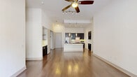 Located at 3551 Wilshire Way in Richardson, TX, this well-appointed single-story home offers four bedrooms and three bathrooms across a thoughtfully designed floor plan. The open-concept living and kitchen area is a standout feature, boasting soaring ceilings, rich hardwood flooring, and generous natural light streaming in through large windows and a glass door. A ceiling fan with integrated track lighting anchors the living space, creating a bright and airy atmosphere.

The kitchen is both stylish and functional, centered around a large island with a built-in sink and crisp white countertops. Dark espresso cabinetry provides striking contrast, complemented by a tile backsplash, stainless steel appliances including a French door refrigerator, and elegant pendant lighting overhead. A built-in shelving nook and additional cabinetry add practical storage.

The bedrooms offer plush carpeting and tall ceilings, with several rooms featuring windows that bring in outdoor views and natural light. Closets provide ample storage with built-in shelving. The bathrooms are finished to a modern standard — one features a walk-in glass-enclosed shower with large-format tile and grab bars, while another includes a full soaking tub with tiled surround. A connecting hallway ties the layout together cohesively.