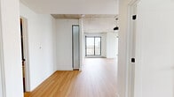 Located at 9450 Rue Meilleur in Montréal, this modern 2-bedroom, 2-bathroom unit offers a thoughtfully designed open-concept layout with a clean, contemporary aesthetic throughout. Exposed concrete ceilings lend an industrial character to the living spaces, beautifully contrasted by crisp white walls and warm light hardwood flooring that flows seamlessly from room to room.

The combined kitchen and living area is anchored by a sleek, galley-style kitchen featuring light wood cabinetry, white quartz countertops, stainless steel appliances, and a tall narrow window that frames city views and draws in natural light. The living area benefits from expansive floor-to-ceiling windows and access to a balcony, offering broad urban vistas of the Montréal skyline.

Both bedrooms are well-proportioned, with large black-framed windows providing ample daylight and city outlooks. The primary bedroom includes a built-in double sliding-door closet. Each room continues the hardwood flooring and exposed concrete ceiling aesthetic for a cohesive feel.

The two bathrooms are finished in contemporary style: one features dark speckled tile, a soaking tub with glass shower enclosure, and chrome fixtures; the second offers a floating vanity with a wide-basin sink, wood-accented shelving, and matching speckled tile flooring. This unit combines urban character with refined modern finishes.