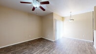 This single-story, 4-bedroom, 2-bathroom home offers a practical and comfortable layout designed to maximize every square foot. The combined living, dining, and kitchen area serves as the heart of the home, featuring durable wood-look flooring that flows seamlessly throughout. A ceiling fan with integrated lighting and a stylish pendant light add character to the space, while a sliding glass door fitted with vertical blinds opens to the exterior, bringing in natural light and outdoor access.

The kitchen is equipped with rich, dark cherry cabinetry, granite countertops, stainless steel appliances including a gas range with overhead microwave, and a pass-through window that connects to the dining area. The bathrooms mirror the kitchen's refined aesthetic, featuring matching granite-topped vanities with warm wood cabinetry and large mirrors.

The four bedrooms are carpeted for comfort, each offering ceiling fans and generous natural light from windows with blinds. The primary bedroom includes a dedicated walk-in closet outfitted with a full rod and wire shelving system. Additional bedrooms are well-sized and connected via a central hallway. Warm beige tones throughout the home create a cohesive, neutral palette ready for personalization.