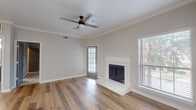 This single-story space is thoughtfully designed with a clean, modern aesthetic throughout. The living area serves as a central gathering space, showcasing warm hardwood-style flooring, crown molding, and a ceiling fan with lighting. A white-surround fireplace with a raised hearth anchors the room, while multiple windows fitted with horizontal blinds allow natural light to filter in. A glass-paned exterior door provides additional brightness and outdoor access.

The kitchen is well-appointed and functional, featuring gray shaker-style cabinetry, white quartz countertops, and a classic subway tile backsplash. A peninsula with an integrated sink and breakfast bar overhang adds workspace and casual dining versatility. Stainless steel appliances, including a refrigerator, electric range, built-in microwave, and dishwasher, complete the setup. In-unit laundry is also accessible from the kitchen area.

The bedroom offers soft carpeting underfoot, a ceiling fan, and generous window coverage that fills the room with natural light. The bathroom includes a soaking tub with tile surround, finished in a crisp all-white palette. Throughout, neutral tones and consistent finishes create a cohesive and comfortable living environment.
