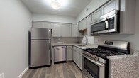 This single-floor residence offers a thoughtfully designed layout that balances functionality and comfort across its key living spaces. The kitchen is a standout feature, equipped with a full suite of stainless steel appliances including a gas range, over-the-range microwave, dishwasher, and full-size refrigerator. Grey shaker-style cabinetry extends to the upper walls, providing generous storage, while speckled granite countertops offer ample prep space. Wood-look plank flooring completes the kitchen's polished appearance.

The open living area transitions seamlessly from the kitchen and is anchored by a striking corner fireplace with a sleek black surround, adding both warmth and visual interest. Soft carpeting extends throughout the living and bedroom areas. A ceiling fan provides additional comfort, while a large sliding glass door floods the space with natural light and offers views of the outdoors.

The bedroom is well-sized with its own ceiling fan, a closet, and a window dressed with vertical blinds. The bathroom features clean white finishes, light tile flooring, and granite countertops. A dedicated laundry room with a full-size washer and dryer adds everyday convenience to this move-in-ready space.