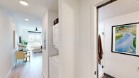 Located at 300 18th St S in Birmingham, Alabama, this modern studio offers a thoughtfully designed open-concept layout that seamlessly integrates living, sleeping, dining, and cooking into a single, well-appointed space. Light wood-look flooring runs throughout, lending warmth and continuity to the interior, while recessed lighting and a ceiling fan provide comfort and ambiance.

The kitchen is a standout feature, outfitted with dark, wood-toned cabinetry that extends to the ceiling for ample storage, stainless steel appliances — including a refrigerator, range, microwave, and dishwasher — and a striking dark tile backsplash that adds visual contrast. A compact dining area with a round marble-top table sits adjacent, making efficient use of the space.

The sleeping area is positioned near a large window that frames views of the surrounding Birmingham cityscape, filling the room with natural light. A full-height storage cabinet integrated into the kitchen zone provides additional organizational flexibility.

A dedicated hallway connects to the bathroom, which features mixed-tone luxury vinyl plank flooring, a glass-enclosed shower, and clean white fixtures. Conveniently nestled in the hallway is a stacked in-unit washer and dryer, adding a practical amenity to this efficiently designed urban residence.