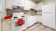 Located at 2074 Forest Hill Rd in Macon, Georgia, this single-floor residence offers a clean, modern interior defined by consistent light wood-style flooring and neutral wall tones throughout. The living areas are bright and open, benefiting from multiple windows fitted with blinds that allow natural light to filter in while maintaining privacy. One area features a sliding glass door with vertical blinds, providing direct access to an outdoor space overlooking a wooded, tree-lined backdrop. A ceiling fan is installed in one of the rooms, adding comfort and functionality. The kitchen is well-appointed with white cabinetry, granite-style countertops, a tile backsplash in a neutral taupe tone, and white appliances including an electric range and refrigerator, alongside a stainless steel sink. The bathroom is neatly finished with a tub-shower combination, a white vanity with a light countertop, and wood-style flooring that ties seamlessly into the rest of the home. The textured ceilings and clean white walls throughout contribute to a bright, well-maintained ambiance. The floorplan, as seen in the dollhouse view, presents a compact yet efficiently organized layout with well-defined living, sleeping, kitchen, and bathroom areas.