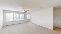 This well-appointed three-story townhome in Kansas City, Missouri offers a thoughtfully designed layout across three distinct levels. The ground floor houses a spacious attached garage complete with an automatic opener, providing convenient private parking and additional storage space. A staircase leads up to the main living level, where an open-concept kitchen and living room create a bright, cohesive entertaining space. The kitchen is outfitted with rich dark-stained cabinetry, stainless steel appliances including a refrigerator with ice maker, range, and microwave, along with light quartz countertops, a subway tile backsplash, and tile flooring. A peninsula with a built-in sink adds both functionality and additional workspace. The living area features plush neutral carpeting and a ceiling fan, with multiple windows that invite natural light. The uppermost floor is the largest level, dedicated to the private quarters. The generously sized primary bedroom boasts soaring ceilings, a ceiling fan, and soft carpeting, with direct access to an en-suite bathroom and a walk-in closet featuring wire shelving. A second bedroom and additional bathrooms — including one with a full tub-shower combo with white subway tile surround and wood-look tile flooring — complete the upper level. With two closets, a hallway, and multiple staircases connecting each floor, this home balances comfort and practicality.
