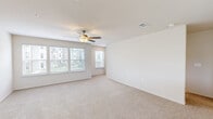 This well-appointed three-story townhome in Kansas City, Missouri offers a thoughtfully designed layout across three distinct levels. The ground floor houses a spacious attached garage complete with an automatic opener, providing convenient private parking and additional storage space. A staircase leads up to the main living level, where an open-concept kitchen and living room create a bright, cohesive entertaining space. The kitchen is outfitted with rich dark-stained cabinetry, stainless steel appliances including a refrigerator with ice maker, range, and microwave, along with light quartz countertops, a subway tile backsplash, and tile flooring. A peninsula with a built-in sink adds both functionality and additional workspace. The living area features plush neutral carpeting and a ceiling fan, with multiple windows that invite natural light. The uppermost floor is the largest level, dedicated to the private quarters. The generously sized primary bedroom boasts soaring ceilings, a ceiling fan, and soft carpeting, with direct access to an en-suite bathroom and a walk-in closet featuring wire shelving. A second bedroom and additional bathrooms — including one with a full tub-shower combo with white subway tile surround and wood-look tile flooring — complete the upper level. With two closets, a hallway, and multiple staircases connecting each floor, this home balances comfort and practicality.