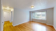 Located at 1610 NE 66th Ave in Portland, OR, this single-floor unit offers four bedrooms, one bathroom, a kitchen, and a connecting hallway within a compact and efficiently organized layout. Warm-toned hardwood floors run throughout the living spaces and bedrooms, contributing a cohesive and inviting aesthetic. Neutral gray walls and white trim provide a clean, versatile backdrop across all rooms. The spacious primary bedroom includes views of surrounding greenery through large windows fitted with blinds, creating a bright and peaceful environment. The additional bedrooms each feature hardwood flooring and natural light, with several offering outdoor views of mature trees. The kitchen is equipped with white cabinetry, laminate countertops, a coil-burner electric range, and a window above the sink that allows natural light to fill the space. The bathroom features classic hexagonal tile flooring and a full tub-shower combination in a crisp white finish. A hallway connects the main areas efficiently. The unit presents a straightforward, functional design with consistent finishes throughout, making it a well-organized multi-bedroom space in a residential Portland neighborhood.