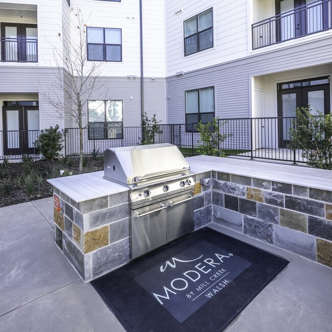 Indulge in outdoor living at its finest on Modera Walsh's lavish outdoor deck, featuring grills, an outdoor kitchen, and inviting al fresco dining areas for memorable gatherings under the open sky. - Modera Walsh