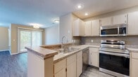 Located at 1630 Crossings Parkway in Westlake, Ohio, this single-floor, 2-bedroom, 2-bathroom residence offers a well-organized layout with a comfortable and functional design throughout. The open-concept living area features durable wood-style flooring, neutral warm-toned walls, a textured ceiling, and a classic fireplace flanked by windows that allow ample natural light to fill the space. The kitchen flows seamlessly from the living area and is equipped with light wood cabinetry, granite-style countertops, stainless steel appliances including a range, microwave, dishwasher, and refrigerator, and a peninsula with a double sink ideal for meal prep and casual dining. The generously sized primary bedroom features plush carpeting and dual windows for natural light, while the second bedroom also offers carpeted flooring and direct window access. Both bathrooms are finished with wood-style flooring, granite-top vanities, and full bathtub-shower combinations. Additional spaces include a utility room and a connecting hallway that ties the layout together efficiently. The overall ambiance is clean, neutral, and move-in ready, making this Westlake residence a practical and comfortable living option.