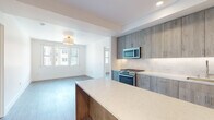 Located at 1258 El Camino Real in Menlo Park, California, this single-floor residence showcases a thoughtfully designed layout with contemporary finishes throughout. The open-concept kitchen serves as a central highlight, featuring wood-toned flat-front cabinetry extending to the ceiling for generous storage, a quartz waterfall island, white tile backsplash, under-cabinet lighting, and a full suite of stainless steel appliances including a gas range, over-the-range microwave, and French door refrigerator. Wood-look flooring flows seamlessly from the kitchen into the adjacent living area, which receives natural light through multiple windows overlooking the surrounding neighborhood.

The bedrooms are bright and well-proportioned, each featuring the same wood-look flooring, clean white walls, and dual windows that invite natural light. A hallway connects the private areas of the residence with well-placed doors providing defined separation between spaces.

The bathrooms are finished with crisp white tile walls accented by dark horizontal tile borders. One bathroom offers a soaking tub with glass panel and tiled surround, while the primary bathroom includes a walk-in glass-enclosed shower, a wood-vanity with quartz countertop, an undermount sink, and a large mirror.