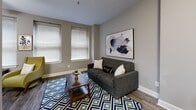 Located at 10 S Main St in the heart of downtown Memphis, Tennessee, this one-bedroom, one-bathroom residence offers a well-designed layout across a single floor. Hardwood-style flooring runs throughout, complemented by neutral gray walls and crisp white trim that create a clean, contemporary aesthetic.

The open-concept living, dining, and kitchen area serves as the centerpiece of the home. The kitchen features white cabinetry, a stainless steel refrigerator, light stone countertops, and a breakfast bar with seating — ideal for casual dining. The living area benefits from multiple windows that allow natural light to fill the space, and a ceiling fan adds comfort overhead.

A dedicated hallway connects the main living space to the private bedroom, which includes multiple windows, a ceiling fan, ample closet storage, and a calm, neutral palette. The full bathroom is outfitted with white cabinetry, a wide vanity with stone-look countertops, a large mirror, and a shower/tub combination.

Additional highlights include a laundry area, utility room, three closets, and a dedicated entrance. The overall ambiance is modern and understated, with thoughtful finishes that balance style and functionality in an efficient, well-organized floor plan.