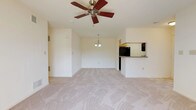 This single-floor residence offers a thoughtfully designed layout with a bright and open feel throughout. The spacious living area serves as the heart of the home, featuring plush carpeting, a ceiling fan, and a fireplace as a central focal point. A sliding glass door floods the room with natural light and provides access to the outdoors. The living space flows seamlessly into a dining area, accented by a pendant light fixture overhead.

The kitchen is efficiently designed with light wood cabinetry, dark laminate countertops, and a full suite of black appliances including a gas range, refrigerator, dishwasher, and built-in microwave. Tile flooring and a window above the sink add to the kitchen's practical and clean aesthetic. A pass-through counter connects the kitchen to the main living area.

The bedrooms are carpeted and well-lit by natural light through windows fitted with blinds. Ceiling fans are present in each room, and the primary bedroom includes closet access. The bathrooms are finished with tile flooring, wood-toned vanity cabinetry, and white fixtures — one featuring a full tub/shower combination. Throughout the residence, neutral warm tones and consistent finishes create a cohesive and comfortable living environment.