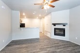 This single-story space in Lubbock, TX offers a well-designed layout with a cohesive mix of finishes throughout. The main living area is anchored by durable wood-look plank flooring that extends across much of the unit, complemented by neutral-toned walls and recessed lighting that create a bright, welcoming atmosphere. A standout feature of the living space is a built-in fireplace framed by a dark wood mantel, adding warmth and visual interest to the room. A ceiling fan overhead provides additional comfort and airflow.

The kitchen is defined by rich, dark espresso cabinetry paired with light granite-style countertops, offering a striking contrast. Black appliances, including a refrigerator, range, and over-the-range microwave, complete the functional kitchen setup. A breakfast bar with decorative corbels connects the kitchen to the living area, providing a convenient spot for casual dining or entertaining.

A carpeted room features French doors that open to an outdoor area, allowing natural light to filter in. The bathroom maintains the same dark cabinetry theme, featuring a granite-top vanity and overhead storage cabinet, paired with wood-look tile flooring for a consistent aesthetic throughout the space.