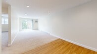 This one-bedroom, one-bathroom residence at 100 Whitehall Road in Amesbury, Massachusetts offers a well-organized single-floor layout with a clean, neutral aesthetic throughout. The living area is bright and open, featuring recessed lighting, soft carpeting, and warm hardwood flooring near the entryway. A sliding glass door floods the space with natural light and provides access to a balcony with views of surrounding greenery, while a wall-mounted air conditioning unit and baseboard heating ensure year-round comfort. The galley-style kitchen is efficiently designed with white cabinetry, granite countertops, stainless steel appliances including a range, microwave, and refrigerator, and durable hardwood flooring. The bedroom is a comfortable, well-proportioned room with plush carpeting, a large window for natural light, a baseboard heater, and a double sliding-door closet offering ample storage. The full bathroom features a tub-shower combination, a white vanity with storage, and neutral tile flooring. Recessed lighting throughout the living and bedroom areas adds a polished touch, while the consistent use of white trim and warm, light tones creates a cohesive and inviting atmosphere throughout the entire residence.