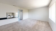 Located in Largo, Florida, this one-bedroom, one-bathroom residence offers a practical and well-organized single-floor layout. The living room is the largest area of the home, featuring neutral-toned carpet, soft gray walls, and a textured ceiling. A sliding glass door opens to a private balcony with scenic outdoor views, allowing natural light to fill the space. Adjacent to the living area, the kitchen is defined by a peninsula counter with dark granite-style countertops, white cabinetry, and wood-style flooring — creating a functional pass-through design that keeps the layout open and connected. The bedroom is a comfortable, carpeted room with access to a dedicated closet, providing practical storage. The bathroom includes wood-style flooring, a vanity with dark countertops, a large mirror with overhead lighting, and a shower-tub combination, all finished in a clean white palette. Throughout the residence, consistent neutral tones, light-filled rooms, and a straightforward layout contribute to an uncluttered, move-in-ready atmosphere well-suited for everyday living in the Largo area.