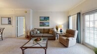 This single-floor residence offers a thoughtfully designed layout that balances comfort and functionality throughout. The entryway welcomes visitors with tile flooring, decorative framed artwork, and a coat rack, setting an organized and inviting tone from the moment you step inside.

The living room serves as the heart of the home, showcasing crown molding, plush wall-to-wall carpeting, and a classic white-mantled fireplace as a focal point. Large windows dressed with teal curtains allow natural light to fill the space, while the open layout creates a comfortable, airy atmosphere.

The kitchen is well-equipped with an abundance of light wood cabinetry, ample counter space with white countertops, a double stainless steel sink, and tile flooring. A breakfast bar adds additional workspace and casual dining potential.

The bedrooms are carpeted and bright, with one featuring a ceiling fan and large windows with an elegant arched transom window that floods the room with natural light. Both bathrooms are outfitted with warm honey-toned wood vanities, wide mirror panels illuminated by Hollywood-style lighting, and generous storage through tall cabinetry and built-in drawers. The tile flooring in each bathroom adds a clean, polished finish.

Overall, the space presents a warm, neutral palette with consistent detailing that creates a cohesive and livable environment throughout.