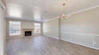 This two-story home offers a thoughtfully designed layout spread across two generously sized floors. The main level features an open-concept kitchen and living area, anchored by a tile-surround fireplace and bathed in natural light from multiple windows. The living and dining space is finished with light wood-look flooring, crown molding, and elegant details including decorative wall paneling and a gold-toned chandelier that adds a refined touch to the space. The kitchen is equipped with white shaker-style cabinetry, granite countertops, stainless steel appliances, and a sink positioned beneath a window overlooking the outdoors. A dedicated laundry room with overhead cabinetry and a full washer and dryer adds everyday convenience. The upper level houses all three bedrooms, each featuring ceiling fans, natural light, and plush carpeting. The generously sized primary bedroom offers notable room to accommodate a full suite of furniture. Four closets throughout the home provide ample storage, including walk-in closets with built-in shelving. The four bathrooms are finished in clean, neutral tones with tiled tub-shower combinations. The exterior presents a classic brick facade surrounded by mature trees, completing this move-in-ready home.