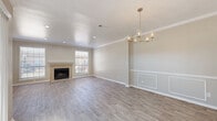 This two-story home offers a thoughtfully designed layout spread across two generously sized floors. The main level features an open-concept kitchen and living area, anchored by a tile-surround fireplace and bathed in natural light from multiple windows. The living and dining space is finished with light wood-look flooring, crown molding, and elegant details including decorative wall paneling and a gold-toned chandelier that adds a refined touch to the space. The kitchen is equipped with white shaker-style cabinetry, granite countertops, stainless steel appliances, and a sink positioned beneath a window overlooking the outdoors. A dedicated laundry room with overhead cabinetry and a full washer and dryer adds everyday convenience. The upper level houses all three bedrooms, each featuring ceiling fans, natural light, and plush carpeting. The generously sized primary bedroom offers notable room to accommodate a full suite of furniture. Four closets throughout the home provide ample storage, including walk-in closets with built-in shelving. The four bathrooms are finished in clean, neutral tones with tiled tub-shower combinations. The exterior presents a classic brick facade surrounded by mature trees, completing this move-in-ready home.