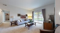 Located at 135 Reynoldsburg New Albany Rd S in Reynoldsburg, Ohio, this single-floor residence offers a comfortable and functional layout with thoughtfully designed living spaces throughout. The living room serves as the heart of the home, featuring plush carpeting, vaulted ceilings, and a large sliding glass door that fills the space with natural light and provides direct access to an outdoor patio with views of the surrounding greenery. The galley-style kitchen is equipped with dark espresso cabinetry, granite-style countertops, hardwood-style flooring, and black appliances including a gas range and dishwasher, providing an efficient and stylish cooking environment. Adjacent to the kitchen, the dining area offers additional hardwood-style flooring and convenient access to the in-unit laundry closet, which houses a full-size side-by-side washer and dryer. The primary bedroom features soft carpeting, a window for natural light, and a dedicated en-suite bathroom. The bathroom is finished with a dark wood vanity, granite-style countertops, hardwood-style flooring, and a shower-tub combination. A second bedroom with carpeting provides flexible use as a guest room or home office. The overall aesthetic is clean and neutral, with light gray walls throughout creating a cohesive and welcoming ambiance.