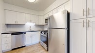 This 2-bedroom, 1-bathroom residence offers a thoughtfully organized single-floor layout that makes efficient use of its space. The living room features light hardwood-style flooring, a ceiling fan, baseboard heating, and windows that bring in natural light and outdoor views of the surrounding greenery and neighborhood. The updated kitchen is a standout, showcasing white shaker-style cabinetry, a classic subway tile backsplash, dark countertops, and a full suite of stainless steel appliances including a gas range, dishwasher, microwave, and refrigerator. Both bedrooms are carpeted and finished in a neutral palette, each offering bifold-door closets with built-in shelving and hanging rods for organized storage. The primary bedroom benefits from dual windows that frame pleasant outdoor views and flood the room with natural light. The bathroom is clean and bright, featuring tile flooring, a white vanity with a gold-toned faucet, a mirrored medicine cabinet, and a tiled shower area. A hallway and dedicated closet provide additional storage. Baseboard heating is present throughout, and the consistent use of light tones and wood-look flooring in the common areas gives the home a cohesive, welcoming ambiance.