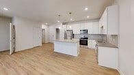 Located in Elkhorn, Nebraska, this well-appointed 1-bedroom, 1-bathroom unit offers a thoughtfully designed single-floor layout that maximizes both comfort and functionality. The open-concept kitchen and living area serves as the heart of the home, showcasing light-toned luxury vinyl plank flooring, recessed lighting, and abundant natural light streaming through large windows and a sliding glass door that opens to a private balcony. The kitchen is a standout feature, equipped with crisp white cabinetry, a classic tile backsplash, stainless steel appliances — including a refrigerator, range, microwave, and dishwasher — and a central island with pendant lighting overhead, providing both additional prep space and a casual dining option. The living area benefits from vaulted ceilings and generous proportions, creating an airy, open atmosphere. The bedroom is a comfortable retreat, finished with plush carpeting, a ceiling fan, and a sizable window that fills the room with natural light. Two closets offer ample storage throughout the unit. The bathroom features white cabinetry, a well-lit vanity mirror, and matching flooring, maintaining the clean, modern aesthetic found throughout the space. Neutral tones and contemporary finishes lend the entire unit a fresh, move-in-ready appeal.