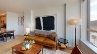 Located at 2500 Fulton Place in Reston, Virginia, this single-floor residence presents a thoughtfully designed contemporary living space with a clean, modern aesthetic throughout. Light hardwood flooring flows seamlessly across the open-concept layout, connecting the kitchen, dining, and living areas into a cohesive and functional space.

The kitchen is outfitted with flat-front light wood cabinetry extending from floor to ceiling, dark stone countertops, and a slate-toned subway tile backsplash. Stainless steel appliances, including a gas range, built-in microwave, and refrigerator, complete the well-equipped cooking space. The kitchen opens directly into the dining area and living room, facilitating an effortless flow for everyday living and entertaining.

The living room features crisp white walls and large windows that invite ample natural light while framing views of the surrounding Reston landscape. The bedroom is a serene retreat with hardwood floors, neutral walls, and a window offering outdoor views. The bathroom includes a glass-enclosed walk-in shower finished with white subway tile, polished fixtures, and a beige tile floor, delivering a clean and refined aesthetic. Overall, the space conveys a contemporary, well-appointed character throughout.