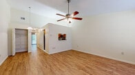 This single-floor, 2-bedroom, 1-bathroom residence offers a well-organized layout across a comfortable footprint. The combined living and dining area is a standout space, featuring vaulted ceilings with a ceiling fan, warm wood-look laminate flooring, and a pass-through window that visually connects to the kitchen. A sliding glass door leads to a screened patio overlooking lush greenery, filling the room with natural light. A secondary entry point with a large window further brightens the living space.

The kitchen is efficiently designed with warm honey-toned wood cabinetry, dark granite countertops, white tile flooring, and stainless steel appliances including a refrigerator, range, and built-in microwave. A dedicated laundry room with washer and dryer hookups and an HVAC unit adds practical utility.

Both bedrooms feature wood-look laminate flooring and ceiling fans. The primary bedroom is a generously sized retreat. The shared bathroom includes a tub-shower combination with tile surround, a wood vanity with granite countertop, and classic mosaic tile flooring. A hallway and closet complete the functional layout of this well-appointed residence.