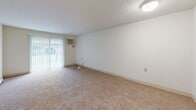 Located at 8 Derry Way in Derry, New Hampshire, this 2-bedroom, 1-bathroom unit offers a straightforward single-floor layout designed for comfortable everyday living. The living area features wall-to-wall carpeting, a sliding glass door with vertical blinds that allows natural light to filter in, and a wall-mounted air conditioning unit. The space has a clean, neutral palette throughout with white walls and standard ceiling fixtures.

The spacious primary bedroom is a standout feature of this unit, offering generous floor space, plush carpeting, and two closets — including a roomy reach-in closet with a hanging rod for ample storage. The second bedroom is also carpeted and includes its own closet with sliding panel doors and a hanging rod, providing practical storage. Both bedrooms feature baseboard heating, ensuring warmth during New Hampshire winters.

The full bathroom is finished with warm wood-tone vinyl plank flooring, a white vanity with a broad countertop and integrated sink, a well-lit vanity mirror, and a full tub-shower combination with a clean white surround. The kitchen area, visible in the floor plan, includes essential appliances and cabinetry. Overall, the unit presents a clean, functional living environment in a residential Derry neighborhood.