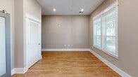 Located at 2332 McClintock Rd in Charlotte, NC, this well-appointed one-bedroom, two-bathroom unit offers a thoughtfully designed layout that maximizes every square foot. The open-concept kitchen and living area anchors the home, featuring warm hardwood flooring, neutral taupe walls, and recessed lighting throughout. The kitchen is a standout, outfitted with white shaker-style cabinetry extending to the ceiling, a decorative lattice wine rack, mosaic tile backsplash, gray countertops, stainless steel appliances including a range, microwave, dishwasher, and refrigerator, plus a double-pane window that fills the space with natural light. A glass door provides direct outdoor access. The living room is bright and open, with large windows dressed in white blinds offering views of mature trees. The spacious bedroom features a tray ceiling with a ceiling fan, hardwood floors, a window with outdoor views, and a walk-in closet with built-in shelving. The two bathrooms are well-finished, with one showcasing a floor-to-ceiling tiled walk-in shower with a built-in bench, glass enclosure, and mosaic accent strip — a truly luxurious detail. Warm tile flooring and a white vanity with dark countertop complete the bathroom. A hallway and closet round out this efficiently designed home.