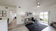 This single-floor residence showcases a clean, contemporary design throughout, with light wood-style flooring and a crisp white color palette that unifies each space. The living area is notably airy, benefiting from vaulted ceilings and a ceiling fan overhead. A sliding glass door opens directly to an outdoor patio, allowing natural light to fill the room while offering views of greenery and a waterway beyond. The open layout accommodates both a seating and media area with ease.

The kitchen is efficiently arranged with light wood cabinetry extending to the ceiling, white appliances including a range, over-the-range microwave, dishwasher, and refrigerator, and ample counter space along continuous runs of cabinetry on multiple walls.

The two bedrooms are well-proportioned, each featuring light-filtering window blinds that bring in natural light. The primary bedroom offers generous wall space suited for a full bedroom suite. A walk-in closet with wire shelving provides organized storage.

The bathroom features light wood-toned cabinetry, a wide vanity with an extended mirror, and a separate shower enclosure, all finished in a neutral, modern palette consistent with the rest of the residence.