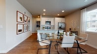 This thoughtfully designed single-floor residence offers a seamless open-concept layout that connects the kitchen, dining, and living areas into one cohesive and functional living space. The kitchen is a standout feature, outfitted with crisp white shaker cabinetry, a subway tile backsplash, granite countertops, and a full suite of stainless steel appliances including a range, microwave, dishwasher, and French door refrigerator. A generous island with seating provides additional workspace and casual dining. Wood-look flooring flows throughout, lending warmth and continuity to the entire home. The dining area sits adjacent to the kitchen, offering an ideal space for entertaining, while the living area benefits from large windows that invite an abundance of natural light and outdoor views. The bedrooms are well-proportioned, each featuring large windows, ceiling fans, and wood-look flooring. The bathrooms mirror the kitchen's refined aesthetic, featuring granite-topped white vanities, large mirrors, and tub-shower combinations with clean tile surrounds. Recessed lighting throughout, neutral wall tones, and a consistent design language give the residence a polished, modern ambiance suited for comfortable everyday living.