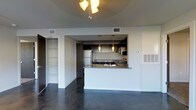 This 2-bedroom, 2-bathroom single-floor residence offers a clean, contemporary design with an open-concept layout that seamlessly connects the living and kitchen areas. The polished concrete floors throughout lend an urban, industrial character while remaining easy to maintain and visually striking.

The kitchen is a standout feature, accessible via a pass-through peninsula topped with granite countertops that double as a breakfast bar. Pendant lighting hangs above the peninsula, adding both task illumination and a stylish focal point. The kitchen is equipped with stainless steel appliances, including a refrigerator and range, complemented by dark cabinetry that provides a bold contrast against the lighter walls and countertops.

The open living area benefits from a ceiling fan, ensuring year-round comfort. Thoughtful built-in shelving is visible adjacent to the kitchen, offering practical storage solutions. The overall color palette — neutral walls, dark cabinetry, and polished floors — creates a cohesive, modern aesthetic throughout the space.

With two full bathrooms and two bedrooms, this residence is well-suited for a variety of living arrangements, offering both functionality and a refined, contemporary style throughout.