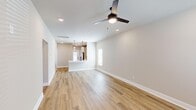 Located at 300 Intergraph Way in Madison, Alabama, this single-story home offers a clean, modern design with thoughtful details throughout. The open-concept living and kitchen area serves as the heart of the home, featuring warm light wood-tone flooring, neutral beige walls, recessed lighting, and a ceiling fan that enhances the bright, airy atmosphere. The kitchen is well-equipped with white shaker-style cabinetry, light quartz countertops, stainless steel appliances including a refrigerator, electric range, and built-in microwave, as well as a stainless undermount sink with a matte black faucet. A peninsula countertop provides additional workspace and casual seating potential. The primary bedroom is a generously sized retreat with dual windows for natural light, a ceiling fan, and access to a walk-in closet outfitted with wire shelving systems. The second bedroom also features a ceiling fan, natural light, and built-in closet storage. Both bathrooms are finished with wood-look flooring, white vanities with matte black hardware, and glass-enclosed walk-in showers. A dedicated laundry room includes a full-size washer and dryer with overhead shelving. The hallway connects all spaces seamlessly, completing this well-designed and move-in-ready home.
