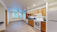 Located at 916 N 143rd St in Seattle, Washington, this two-bedroom, one-bathroom home offers a thoughtfully designed single-floor layout that maximizes its compact footprint. Light-toned luxury vinyl plank flooring runs throughout, creating a cohesive and easy-to-maintain aesthetic across all rooms.

The kitchen is a functional centerpiece of the home, featuring warm honey-toned wood cabinetry with ample upper and lower storage, dark countertops, a built-in range hood, and a full suite of white appliances including a dishwasher, electric range, and refrigerator. Recessed lighting illuminates the space, which flows openly into the adjacent living area. A window allows natural light to filter in, adding to the bright, airy feel.

Both bedrooms offer clean, neutral walls and continued plank flooring. The primary bedroom is a comfortable size, while the second bedroom features a window with outdoor views of the surrounding neighborhood. Each bedroom is served by its own dedicated closet — both equipped with wire shelving systems that maximize vertical storage space, with the primary closet offering a walk-in configuration.

The bathroom is neatly appointed with a full tub-and-shower surround, a wood-tone vanity with a white countertop, a wall-mounted mirror, and recessed overhead lighting. The overall ambiance of the home is clean, modern, and move-in ready.