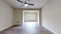 Located at 1460 Oakcrest Rd in Columbia, SC, this well-designed 2-bedroom, 2-bathroom home offers a comfortable and functional single-floor layout, including a sunroom that adds extra living space and natural light. The open living and dining area features durable hardwood-style flooring, neutral warm-toned walls, and a ceiling fan with light fixture, creating a bright and airy atmosphere. A large picture window in the adjoining sunroom space invites in generous natural light and outdoor views of surrounding greenery. The galley-style kitchen is equipped with rich medium-toned wooden cabinetry, dark granite-style countertops, black appliances, and a double sink — offering both style and practicality. The two bedrooms are carpeted for comfort, with the primary bedroom providing a generous footprint, multiple windows with tree views, and ample wall space. The second bedroom also features the same neutral palette and plush carpeting. Both bathrooms include hardwood-style flooring, with one featuring a full soaking tub and shower combination with a dark wood vanity. A dedicated laundry area includes wire shelving and hookups for added convenience. Hallways connect the rooms seamlessly throughout this thoughtfully laid-out home.