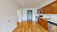 Located at 3030 S Water St in Pittsburgh's South Side neighborhood, this one-bedroom, one-bathroom unit offers a thoughtfully laid-out floor plan across a single level. The open living and kitchen area greets you upon entry, featuring warm-toned wood cabinetry that extends floor to ceiling, bright white countertops, and a full suite of stainless steel appliances including a range, built-in microwave, and dishwasher. Durable hardwood-style flooring runs throughout the main living and kitchen areas, adding warmth and easy maintenance to everyday living. A hallway connects the main living space to the private bedroom and bathroom, providing a clear and functional flow. The bedroom is comfortably sized, finished with soft carpeting and a window that frames views of lush greenery — offering a calm, natural backdrop. The bathroom continues the cohesive design aesthetic with large-format tile flooring, a wood-toned vanity, and a full tub and shower combination. Throughout the unit, crisp white walls and clean lines lend a modern, move-in-ready feel. The overall ambiance is bright, functional, and well-appointed, making this an ideal space in a convenient Pittsburgh location.