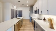 Located at 245 Beacon Town Dr in Huntersville, NC, this thoughtfully designed one-bedroom, one-bathroom unit offers a well-utilized single-floor layout with modern finishes throughout. The open-concept living and kitchen area is anchored by a central island with a quartz countertop and matte black faucet, complemented by warm wood-look luxury vinyl plank flooring that runs throughout the space. The kitchen features a two-tone cabinet scheme — white upper shaker-style cabinets paired with grey lower cabinets — set against a classic white subway tile backsplash. A full suite of stainless steel appliances includes a side-by-side refrigerator with ice and water dispenser, electric range, built-in microwave, and dishwasher. Pendant lighting and recessed ceiling lights provide layered illumination. The bedroom is a comfortable and quiet retreat, featuring a ceiling fan, a large window with outdoor views, and light-toned flooring. The bathroom includes a tub/shower combination with white tile surround and matte black fixtures, with convenient access to a dedicated closet with built-in shelving. The unit's clean, neutral palette and contemporary design elements create a bright, cohesive living environment throughout.