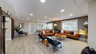 Located at 2508 Main St in Forest Grove, Oregon, this thoughtfully designed single-floor space blends modern aesthetics with a warm, welcoming atmosphere. Light wood-look flooring runs throughout, complementing neutral warm-toned walls and crisp white trim that create a cohesive, contemporary feel.

The main lounge area is generously proportioned, featuring recessed lighting, large windows with white shutters that invite abundant natural light, and an electric fireplace set into a shiplap-clad accent wall with a wood mantle — serving as a natural focal point. Cognac leather sofas, black metal accent chairs, and live-edge wood coffee tables furnish the space with a modern-rustic character.

A dedicated dining area accommodates a long communal table surrounded by metal café-style chairs, ideal for group gatherings. Adjacent to this is a hallway with a reception-style pass-through counter and seating nook, offering a more private setting.

The kitchenette is well-appointed with white shaker cabinetry, granite-look countertops, stainless steel appliances including a refrigerator, dishwasher, and microwave, along with a coffee station. A game room with a pool table rounds out the amenities, adding a recreational dimension to this versatile community space.