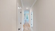 Located at 6900 Bulldog Ln in Carthage, NC, this thoughtfully designed 3-bedroom, 2-bathroom single-story home offers a clean, modern aesthetic throughout. Light wood-look flooring flows seamlessly across the entire layout, creating a warm and cohesive feel.

The open-concept living, dining, and kitchen area serves as the heart of the home. The kitchen is outfitted with crisp white shaker cabinets, dark matte hardware, grey countertops, a deep undermount sink, and stainless steel appliances including a refrigerator, range, and microwave. A central island with pendant lighting adds both function and style.

The living area features crown molding, a ceiling fan, and recessed lighting, while French doors with flanking windows flood the space with natural light and provide access to the balcony. Hallways are bright and well-proportioned, lined with clean white trim and matte black door hardware.

Each bedroom is comfortably sized, ceiling fan-equipped, and finished with the same light flooring. The primary bedroom offers a generous footprint with ample closet space. The bathrooms feature white cabinetry, dark countertops, wood-tone flooring, and matte black fixtures. A dedicated laundry room with a full-size washer and dryer and built-in shelving adds everyday convenience.