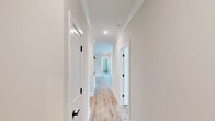 Located at 6900 Bulldog Ln in Carthage, NC, this thoughtfully designed 3-bedroom, 2-bathroom single-story home offers a clean, modern aesthetic throughout. Light wood-look flooring flows seamlessly across the entire layout, creating a warm and cohesive feel.

The open-concept living, dining, and kitchen area serves as the heart of the home. The kitchen is outfitted with crisp white shaker cabinets, dark matte hardware, grey countertops, a deep undermount sink, and stainless steel appliances including a refrigerator, range, and microwave. A central island with pendant lighting adds both function and style.

The living area features crown molding, a ceiling fan, and recessed lighting, while French doors with flanking windows flood the space with natural light and provide access to the balcony. Hallways are bright and well-proportioned, lined with clean white trim and matte black door hardware.

Each bedroom is comfortably sized, ceiling fan-equipped, and finished with the same light flooring. The primary bedroom offers a generous footprint with ample closet space. The bathrooms feature white cabinetry, dark countertops, wood-tone flooring, and matte black fixtures. A dedicated laundry room with a full-size washer and dryer and built-in shelving adds everyday convenience.