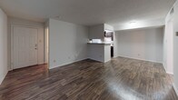 Located at 425 Bernard in Denton, Texas, this single-story 2-bedroom, 2-bathroom unit offers a functional and cohesive interior design throughout. Rich, dark wood-style flooring runs consistently across all living areas, complementing the neutral gray walls and white baseboards to create a clean, modern aesthetic. Textured ceilings are present throughout the unit.

The open living area is spacious and connects directly to the kitchen via a peninsula-style pass-through counter finished with a granite-look surface. The kitchen features dark espresso cabinetry, mosaic tile backsplash, white appliances including an electric range and refrigerator, and ample overhead storage. The layout allows for easy interaction between the kitchen and living spaces.

Both bedrooms are generously proportioned, each equipped with a ceiling fan with light kit and windows that allow natural light to filter in. One bedroom includes direct access to a walk-in closet and an en-suite bathroom, providing added privacy and convenience.

Both bathrooms mirror each other in design, featuring dark espresso vanity cabinetry, granite-look countertops, a single sink, a tub-shower combination with white tile surround, and wood-style flooring for a consistent finish throughout the unit.