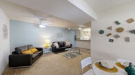 Located at 3205 NW 83rd St in Gainesville, Florida, this single-floor residence offers a well-organized layout designed for comfortable everyday living. A carpeted hallway with clean white walls and a security system panel serves as the central connector between the home's key areas.

The living room is generously sized, featuring soft carpet flooring, light blue-gray walls, and a ceiling fan overhead. Track lighting adds to the bright, open atmosphere, and the room provides ample space for multiple seating arrangements.

The kitchen is equipped with tile flooring, cream cabinetry, a full-size refrigerator, an electric range, and a dishwasher. The light blue accent wall adds a welcoming touch to the functional space.

The bedrooms feature carpet flooring, ceiling fans, and windows that allow natural light to filter in. Each room offers comfortable proportions suitable for a bed and workspace.

The bathroom includes tile flooring, a vanity with a mirror and overhead lighting, a toilet, and a tub-shower combination. The in-unit laundry room is a standout practical feature, housing a full-size washer and dryer alongside a water heater, with wire shelving for additional storage.

Overall, this residence presents a clean, functional layout with consistent finishes throughout.