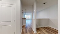 This single-floor residence is thoughtfully arranged to maximize an open, flowing layout. The living area is a generously sized, light-filled space finished with warm hardwood-style flooring that extends throughout the main areas, creating a cohesive and inviting atmosphere. Large windows in the bedrooms allow natural light to filter in while offering views of the surrounding neighborhood.

The kitchen is a standout feature, equipped with white shaker-style cabinetry, granite countertops, and stainless steel appliances including a refrigerator, gas range, and microwave. A peninsula with an overhanging countertop provides a casual dining or workspace, illuminated by pendant lighting above. White subway tile backsplash adds a clean, modern touch to the cooking area.

The bedrooms are carpeted for comfort and each features sizable windows. One bedroom includes a closet with an overhead vent, reflecting practical design. The bathroom is finished with large-format tile flooring, white cabinetry, a granite-topped vanity, and a tub-shower combination with tile surround. A grab bar is also present, adding a functional accessibility element. Neutral gray-toned walls and crisp white trim unify the space with a clean, contemporary character.