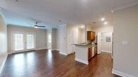 This well-appointed 3-bedroom, 2-bathroom single-story home in Baton Rouge, Louisiana offers a comfortable and functional layout. The open-concept living and kitchen area serves as the heart of the home, featuring rich hardwood-style flooring, crown molding, and ceiling fans throughout. Natural light flows in through French doors and windows fitted with blinds, enhancing the warm, neutral color palette of the walls.

The kitchen is thoughtfully designed with warm wood cabinetry, dark countertops, and white appliances including a range, dishwasher, refrigerator, and built-in microwave. A peninsula provides additional prep space and connects seamlessly to the living area. An in-unit laundry area is conveniently accessible from the kitchen.

The generously sized primary bedroom features plush carpeting, a ceiling fan, and a walk-in closet. Its en-suite bathroom offers an expansive white vanity with ample storage and a large mirror. Two additional bedrooms also feature carpet and ceiling fans, providing comfortable secondary living spaces.

The second full bathroom includes a white vanity, tub-shower combination, and hardwood-style flooring. Crown molding and consistent finishes throughout the home create a cohesive, polished aesthetic, making this Baton Rouge residence a practical and inviting place to call home.