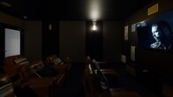 Located at 2001 Dogwood Dr in Fredericksburg, Virginia, this dedicated home theater room delivers an immersive, cinema-quality experience within a single-floor layout. The room is designed with a deliberately dark, dramatic aesthetic — deep charcoal and near-black walls absorb light and enhance contrast, creating an atmosphere reminiscent of a private screening room. Ambient wall sconces provide subtle, controlled illumination that sets the mood without disrupting the viewing experience. The seating arrangement consists of multiple rows of rich brown leather recliners, accented with striped throw pillows, and tiered to ensure unobstructed sightlines from every seat. A large flat-panel display serves as the focal point of the front wall, flanked by wall-mounted surround sound speakers strategically positioned throughout the room for balanced audio. Decorative macramé wall hangings and textured art panels add a personalized, bohemian touch to the otherwise sleek, dark interior. Recessed ceiling speakers further contribute to the multi-dimensional audio setup. A frosted-glass door provides a clean, private entrance to the space. The overall design is thoughtfully optimized for entertainment, combining comfort, acoustics, and visual style into a cohesive and functional private theater experience.