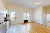 This 1-bedroom, 1-bathroom unit offers a thoughtfully organized layout across a single floor. The open living and kitchen area blends two distinct flooring materials — warm hardwood and classic marble-style tile — creating a natural visual separation between spaces. A cast-iron radiator and multiple double-hung windows allow natural light to pour in while offering views of the surrounding urban streetscape. An exposed brick wall near the entryway adds architectural character, complemented by tall ceilings that enhance the sense of openness throughout.

The kitchen is well-equipped with a full suite of stainless steel appliances, including a gas range, microwave, dishwasher, and refrigerator. White shaker-style cabinetry extends to the ceiling for ample storage, while a mosaic tile backsplash adds a refined touch. A coat closet sits conveniently near the front door.

The bedroom is a comfortable, light-filled retreat featuring hardwood floors, dual windows with urban views, a baseboard heater, and a built-in closet with shelving. The bathroom is finished with classic white subway tile walls, a hexagonal mosaic tile floor, a soaking tub with shower, and a small window for natural ventilation — delivering a clean, timeless aesthetic throughout.