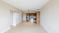 This well-designed single-floor unit offers a clean, modern aesthetic throughout, highlighted by large-format light tile flooring and warm neutral walls that create a bright, cohesive atmosphere. The open-concept living and dining area flows seamlessly toward a private balcony, where floor-to-ceiling windows and sliding glass doors invite abundant natural light and outdoor views of lush greenery. A stylish sliding barn door serves as a functional architectural accent, connecting the living space to the bedroom areas.

The kitchen is a standout feature, outfitted with flat-front wood-grain cabinetry in a warm tone, granite countertops, a tile backsplash, and a full suite of stainless steel appliances including a French door refrigerator with ice and water dispenser, a wall oven with microwave combo, an electric range, and a dishwasher. Track lighting above the kitchen adds both task illumination and a contemporary touch.

The bedrooms are generously proportioned, each with tile flooring, ceiling fans, and windows that bring in natural light. Ample closet space is provided in the bedroom hallway. The bathroom features a double-sink vanity with granite countertops, wood-grain cabinetry, large-format tile flooring, and a full soaking tub with a tiled surround, delivering a clean and functional finish throughout.