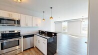 Located at 50-54 Leonard St in Beacon, NY, this well-appointed 2-bedroom, 1-bathroom residence offers a thoughtfully designed single-floor layout. Light-toned hardwood-style flooring runs throughout, creating a cohesive and contemporary feel.

The open-concept kitchen is a standout feature, outfitted with white shaker cabinetry, dark granite countertops, a classic subway tile backsplash, and a full suite of stainless steel appliances including a range, microwave, dishwasher, and refrigerator. Warm pendant lighting above the peninsula adds character and defines the space, which flows seamlessly into the combined dining and living area. The living room is generously sized, bathed in natural light from large multi-pane windows that frame outdoor views of the surrounding Beacon neighborhood.

The spacious primary bedroom benefits from dual windows that invite abundant natural light and outdoor scenery, complemented by an industrial-style ceiling fixture. The second bedroom is equally well-lit with its own window and closet access. With six closets throughout, storage is plentiful. The bathroom features tile flooring, a vessel sink atop a rich dark-wood vanity, and a sleek wall-mounted light fixture. An in-unit laundry area adds everyday convenience to this move-in-ready home.