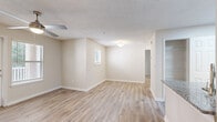 Located at 100 Camellia Ln in Stonecrest, GA, this single-floor, one-bedroom, one-bathroom home offers a thoughtfully designed layout that makes efficient use of every square foot. Light-toned, hardwood-style flooring runs throughout the main living areas, complemented by neutral walls and textured ceilings that create a warm, inviting ambiance.

The open living room is bright and airy, benefiting from natural light through slatted blinds and a ceiling fan overhead. A door leads directly to an outdoor patio area, extending the living space beyond the interior. The layout flows naturally into the kitchen, which stands out as a centerpiece of the home. White cabinetry pairs elegantly with granite countertops, a granite-topped peninsula with an undermount sink, and stainless steel appliances including a refrigerator and electric range.

The bedroom features plush carpeting, multiple windows with views of greenery, a ceiling fan, and a dedicated closet for storage. The bathroom is well-appointed with white cabinetry, granite countertops, an undermount sink, and a tiled tub-shower combination. A dedicated laundry area with in-unit washer and dryer adds everyday convenience, rounding out this well-equipped and comfortable Stonecrest home.