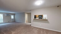 Located in Eden Prairie, MN, this single-floor residence offers a well-organized layout with two bedrooms, two full bathrooms, a combined kitchen and living room, a closet, and an in-unit laundry room. The living room is a generously sized, open area finished with neutral-toned carpet, a wall-mounted air conditioning unit, baseboard heating, and windows that invite natural light and views of surrounding greenery. A private exterior door in the living area adds direct access convenience. The kitchen is equipped with warm wood cabinetry, light stone countertops, and a full suite of black appliances including a refrigerator, range, and over-the-range microwave, all set on light wood-look flooring. The spacious primary bedroom features plush carpet, baseboard heating, and a ceiling fan with light fixture. The second bedroom also offers carpeted flooring and a wall unit for climate control. Both bathrooms include a full tub-shower combo, warm-toned tile flooring, and wood vanities with stone-style countertops. Neutral beige and cream tones are carried consistently throughout the space, creating a cohesive and practical living environment well-suited for everyday comfort.